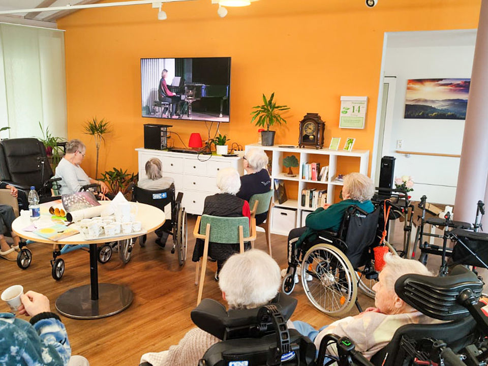 Mehrere ältere Menschen, die gemeinsam Fernsehen schauen.