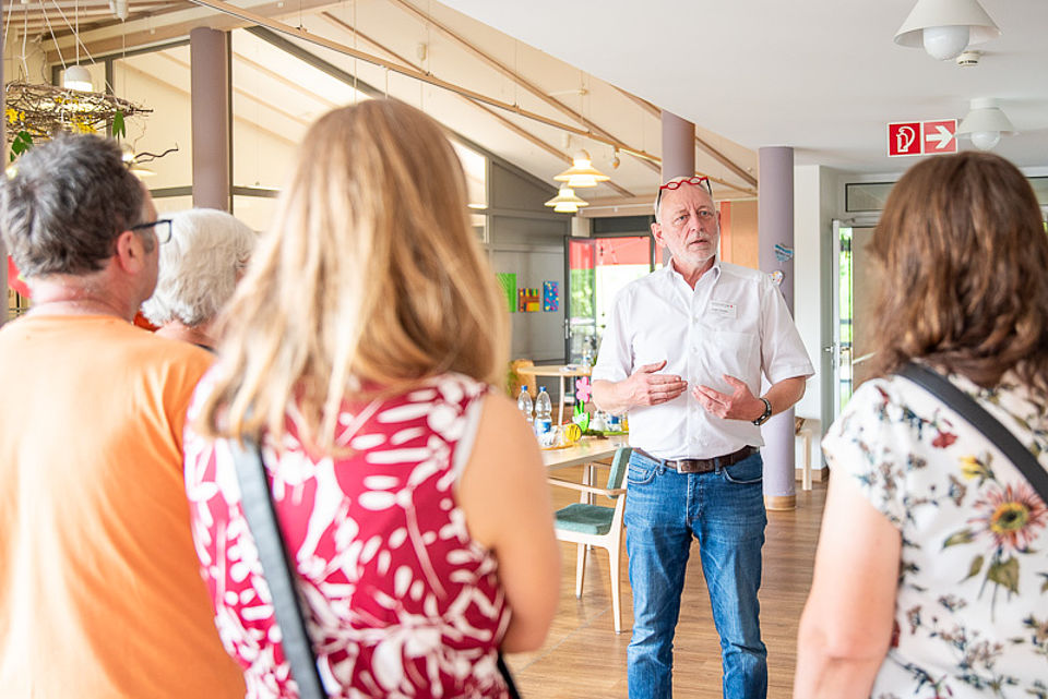Ein Mitarbeiter erklärt Besuchenden die Pflegeeinrichtung.